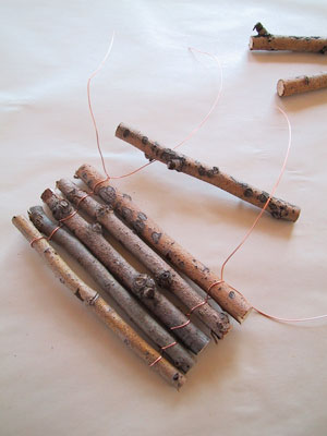 2. Loop 2 lengths of wire or twine around each end of the first twig. Twist once (like you would a twist tie) then put the next twig in place and twist again. Repeat until the raft is big enough. Double twist ends and flatten any sharp wire into the wood with a hammer.